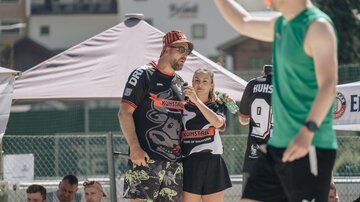 Eine Sportveranstaltung im Freien mit Teilnehmern in sportlicher Kleidung. Im Vordergrund stehen Menschen in einer geselligen Atmosphäre.