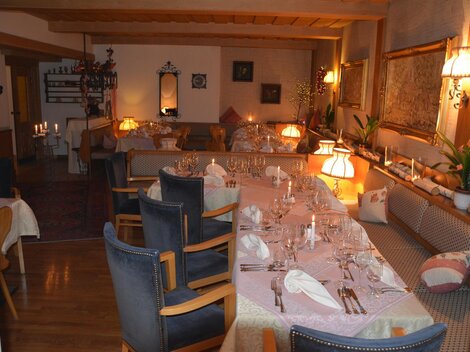 Ein gemütliches Restaurant mit einer langen, gedeckten Tafel und warmem Licht. Die Einrichtung ist einladend und freundlich.