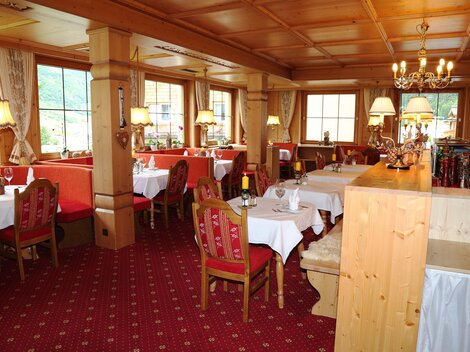 Ein gemütliches Restaurant mit Holzmöbeln und roten Sitzen. Sanfte Beleuchtung schafft eine einladende Atmosphäre.
