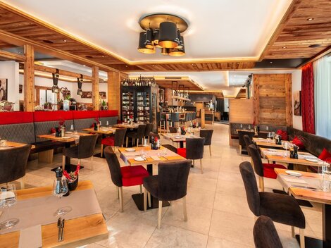 Ein modernes Restaurant mit Holzverkleidung und gemütlicher Sitzgelegenheit. Die Tische sind ordentlich gedeckt und es herrscht eine einladende Atmosphäre.
