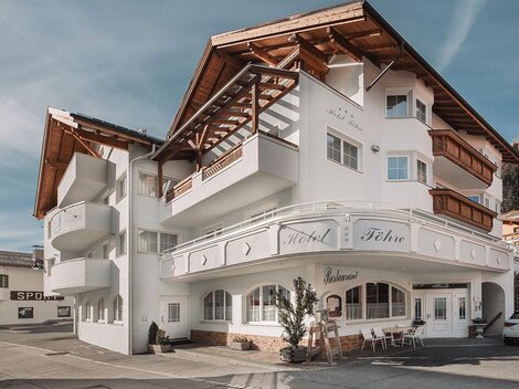 Ein modernes Hotelgebäude mit einem charakteristischen Dach und einer einladenden Fassade. Es liegt in einer malerischen Berglandschaft.