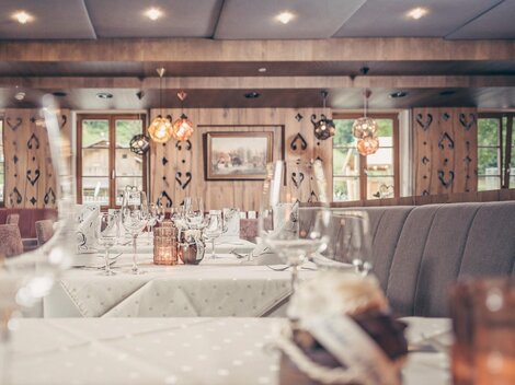 Ein gemütliches Restaurant mit elegant gedeckten Tischen. Weiche Beleuchtung und rustikale Elemente schaffen eine einladende Atmosphäre.