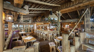 Ein gemütliches Restaurant mit Holzmöbeln und rustikalem Ambiente. Die warme Atmosphäre lädt zum Verweilen und Speisen ein.