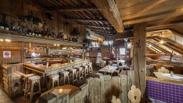 Ein gemütliches Restaurant mit Holzmöbeln und rustikalem Dekor. Die Umgebung wirkt einladend und warm.