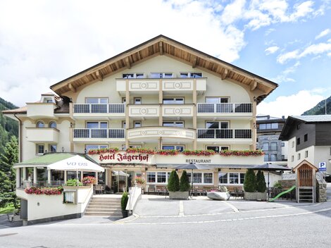 Ein charmantes Hotel mit alpenländischem Design und mehreren Balkonen. Umgeben von Bergen und einer ruhigen Umgebung.