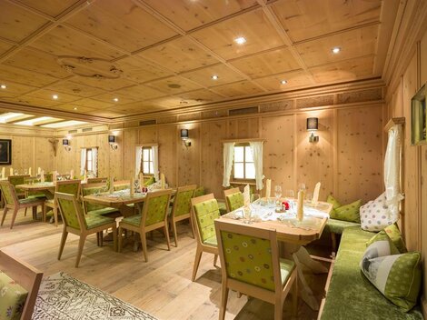 Ein gemütlicher Raum mit Holzwänden und eleganter Einrichtung. Mehrere Tische und Stühle sind bereit für Gäste.
