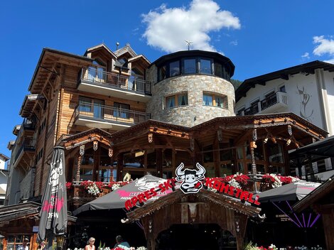 Ein gemütliches Restaurant mit Holzfassade und Terrassen. Blumen und Dekorationen verleihen der Ansicht einen einladenden Charme.