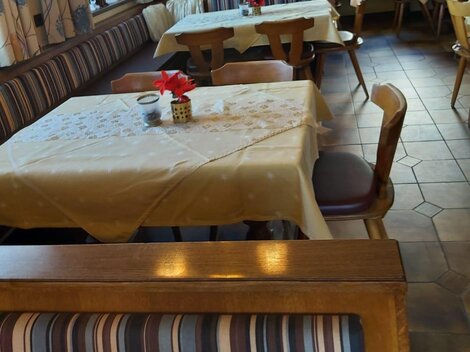 Ein einladendes Restaurant mit schön eingedeckten Tischen und Holzbank. Die Atmosphäre ist gemütlich und freundlich.