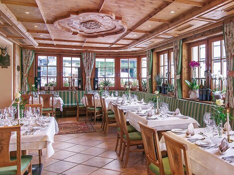 Ein elegantes Restaurant mit Holzmöbeln und gemütlicher Atmosphäre. Die Tische sind festlich mit Gläsern und Blumen dekoriert.