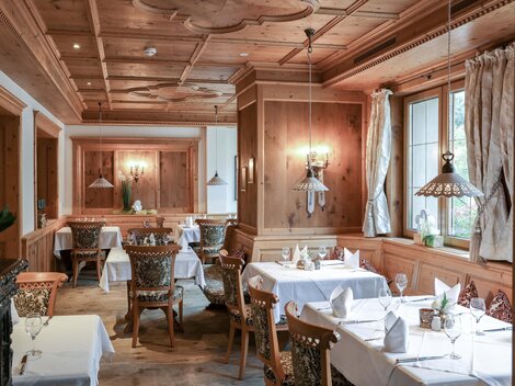 Ein gemütliches Restaurant mit Holzwänden und elegant eingedeckten Tischen. Sanftes Licht sorgt für eine einladende Atmosphäre.
